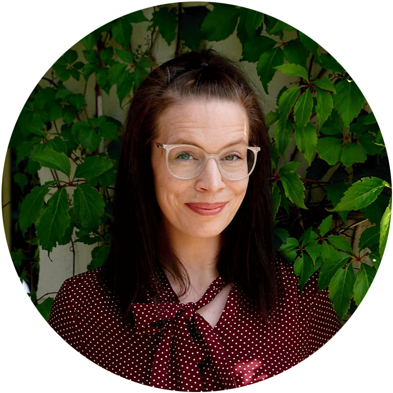 Mitarbeiterin von Pt.nrw mit braunen schulterlangen haaren und einer Brille. Steht vor grünen Pflanzen